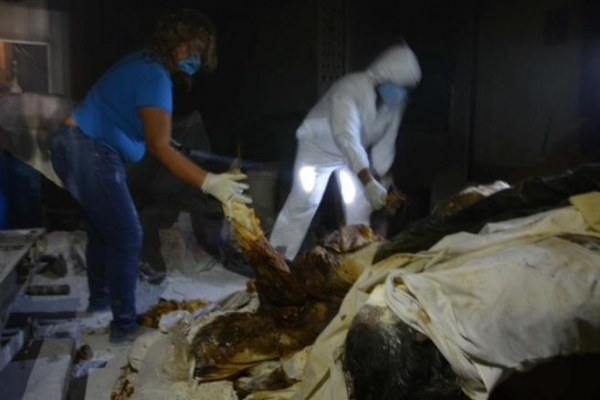 Policías y forenses trabajan en el lugar donde se han encontrado los cuerpos sin vida.