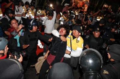 Policías mexicanos detienen un manifestante durante una protesta