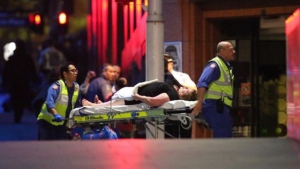 Un herido es trasladado a la ambulancia tras el asalto al café Lindt.
