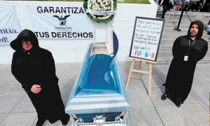 Dos trabajadores del Poder Judicial en Jalisco resguardan un ataúd con una copia de la Constitución, como parte del paro contra la reforma judicial.