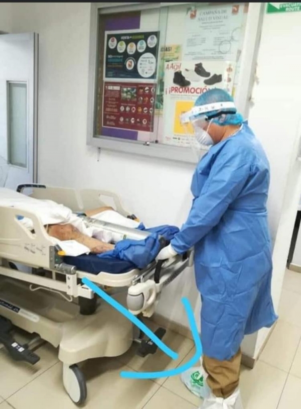 Personal del OPD Servicios de Salud del Municipio de Zapopan (SSMZ), fotografía en que se oberva a un trabajador usando simples bolsas de plástico en sus pies para proteger su calzado mientras atiende a un paciente sospechoso de covid-19.