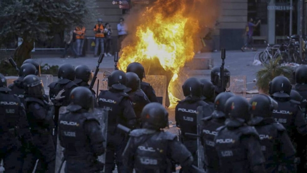 Antidisturbios de la Policia Nacional delante de un gran fuego en Via Laietana, en Barcelona. En vídeo, imágenes de los disturbios en el quinto día de protestas.
