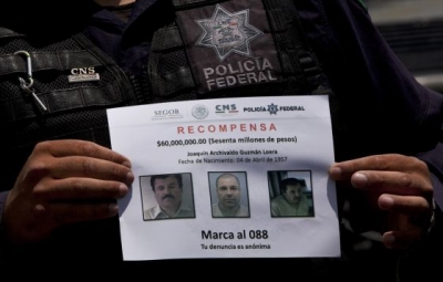 Un policía muestra el letrero de &quot;Se Busca&quot; de El Chapo.