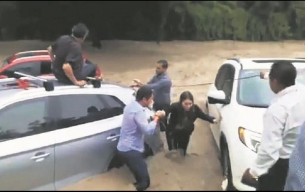 Personas auxiliaron a una joven que quedó atrapada dentro de su vehículo (color rojo) luego del desbordamiento del canal de avenida Patria.
