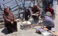 Los palestinos encienden un fuego para cocinar pan en una escuela de la ONU que alberga a personas desplazadas en la ciudad de Gaza el 4 de junio de 2024.