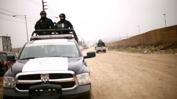 La Policía y los soldados cruzan la valla fronteriza entre México y los EE. UU, en Tijuana, el 13 de marzo del 2018.