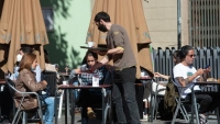 Un camarero sirve a unas clientas en una terraza de un bar de Barcelona 