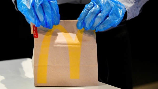 Un empleado con guantes maneja un pedido en un McDonald&#039;s en Arnhem, Países Bajos, el 1 de mayo de 2020.