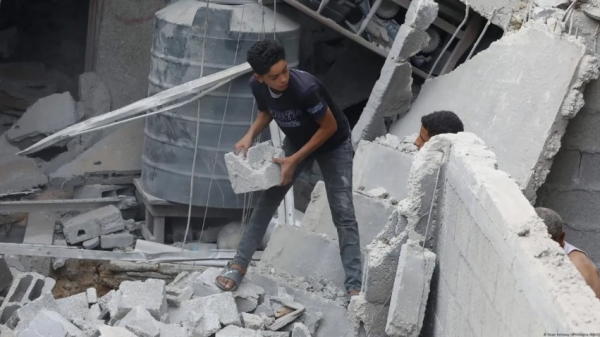Jóvenes residentes palestinos realizan operaciones de búsqueda y rescate entre los escombros de una casa demolida por ataques aéreos israelíes en la Franja de Gaza.