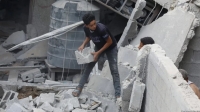 Jóvenes residentes palestinos realizan operaciones de búsqueda y rescate entre los escombros de una casa demolida por ataques aéreos israelíes en la Franja de Gaza.